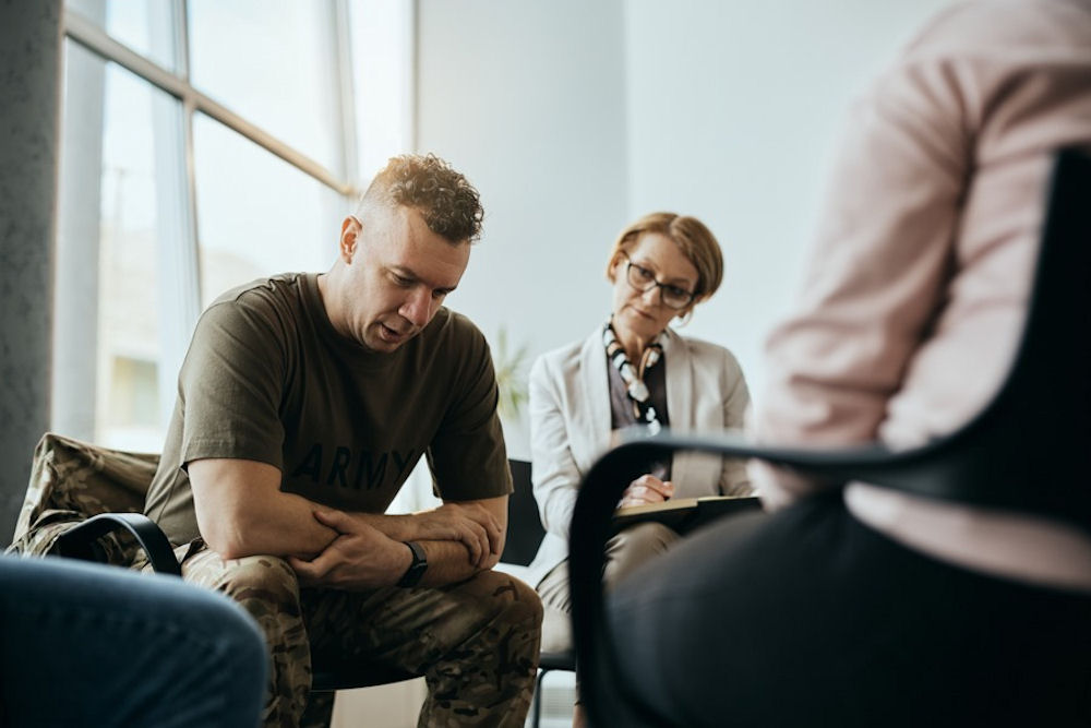 Therapist looking on at man in military fatigues in IOP treatment