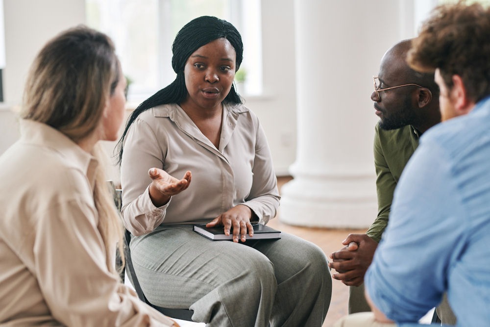 php-addiction-treatment-program Woman with notebook describes a PHP in a group of people