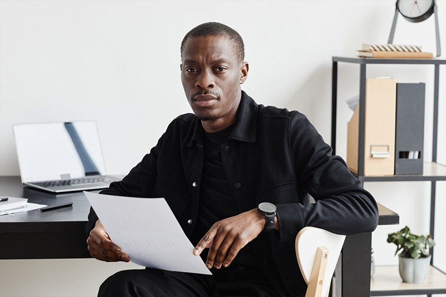 telehealth-treatment-for-addiction Man looks up from reading printed document at desk