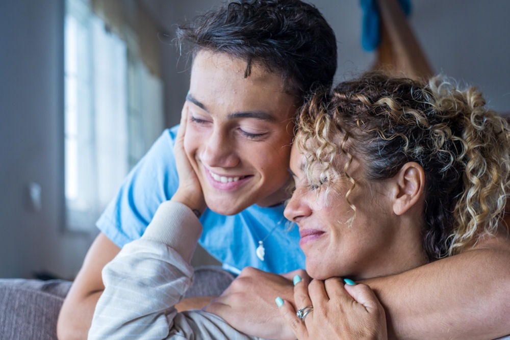 Young man embracing his seated mother during Dual Diagnosis Treatment