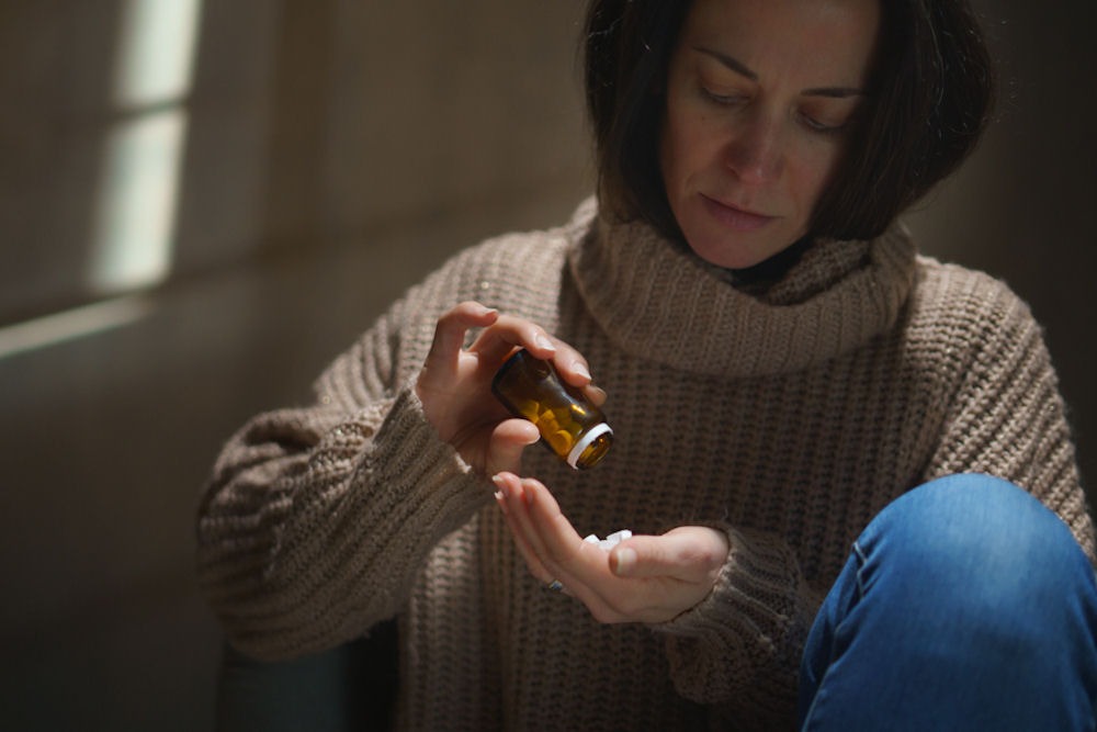 benzodiazepine-addiction-treatment Woman pouring pills into hand while seeking benzodiazepine addiction treatment