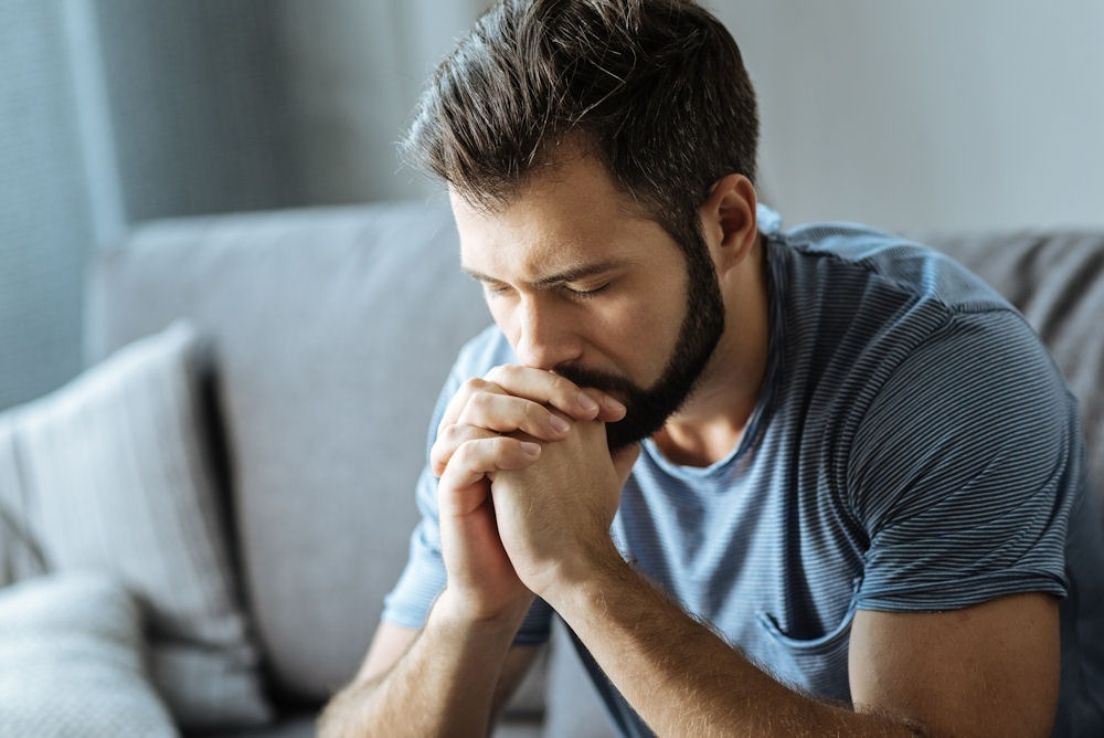 benzodiazepine-addiction Man sitting with hands clasped, reflecting during benzodiazepine addiction treatment