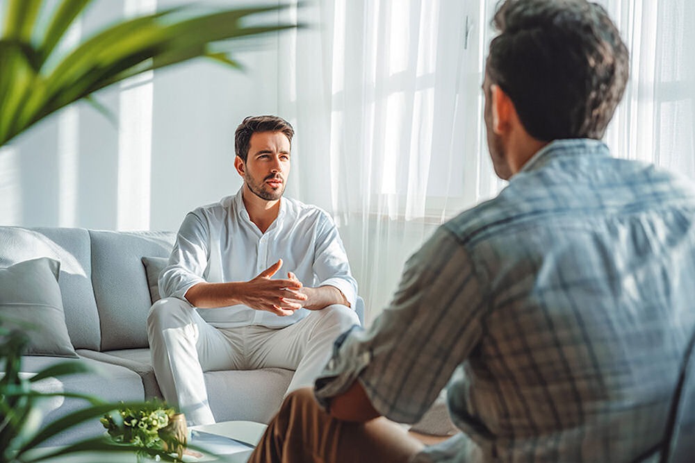 bipolar-and-addiction-treatment-california Man on white couch talking to therapist about bipolar disorder and addiction.