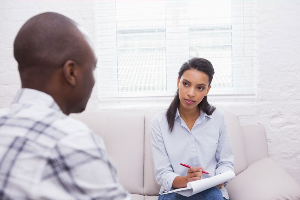 cbt-addiction-west-lake-ca therapist takes notes on notepad while man in CBT for addiction treatment speaks