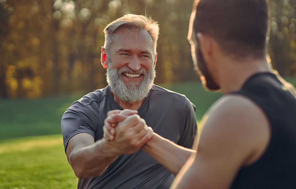 Older man clasping hand of younger man in triumph.