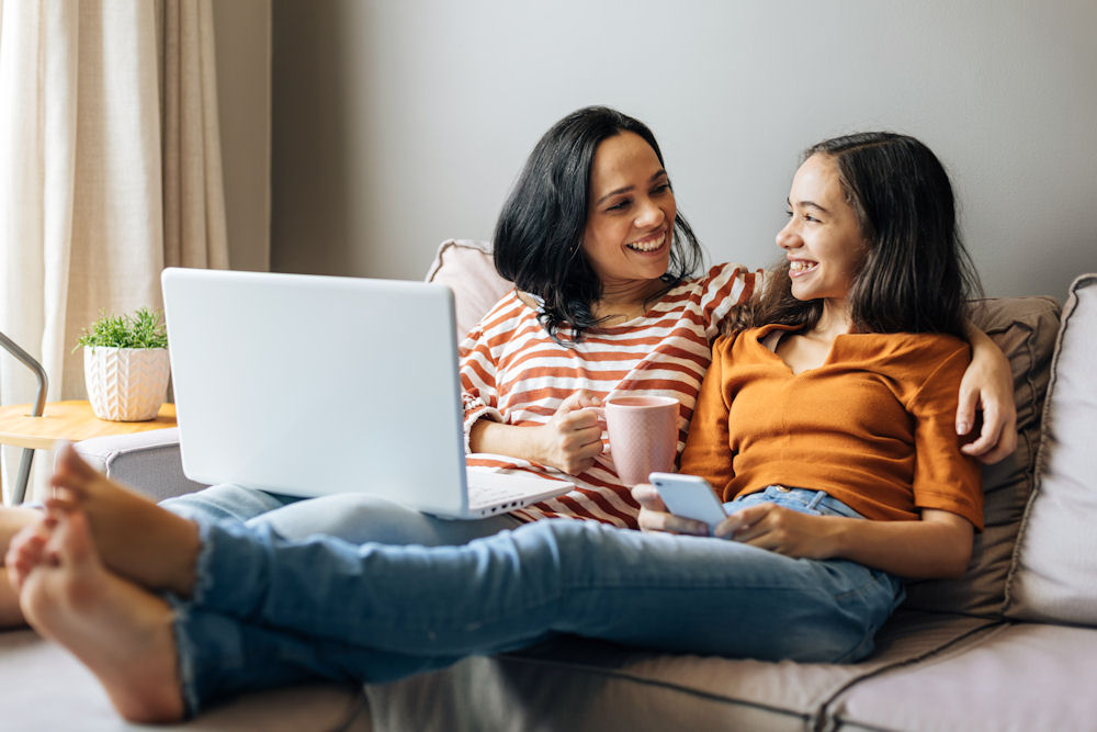 Two women smiling and embracing each other during virtual family therapy.